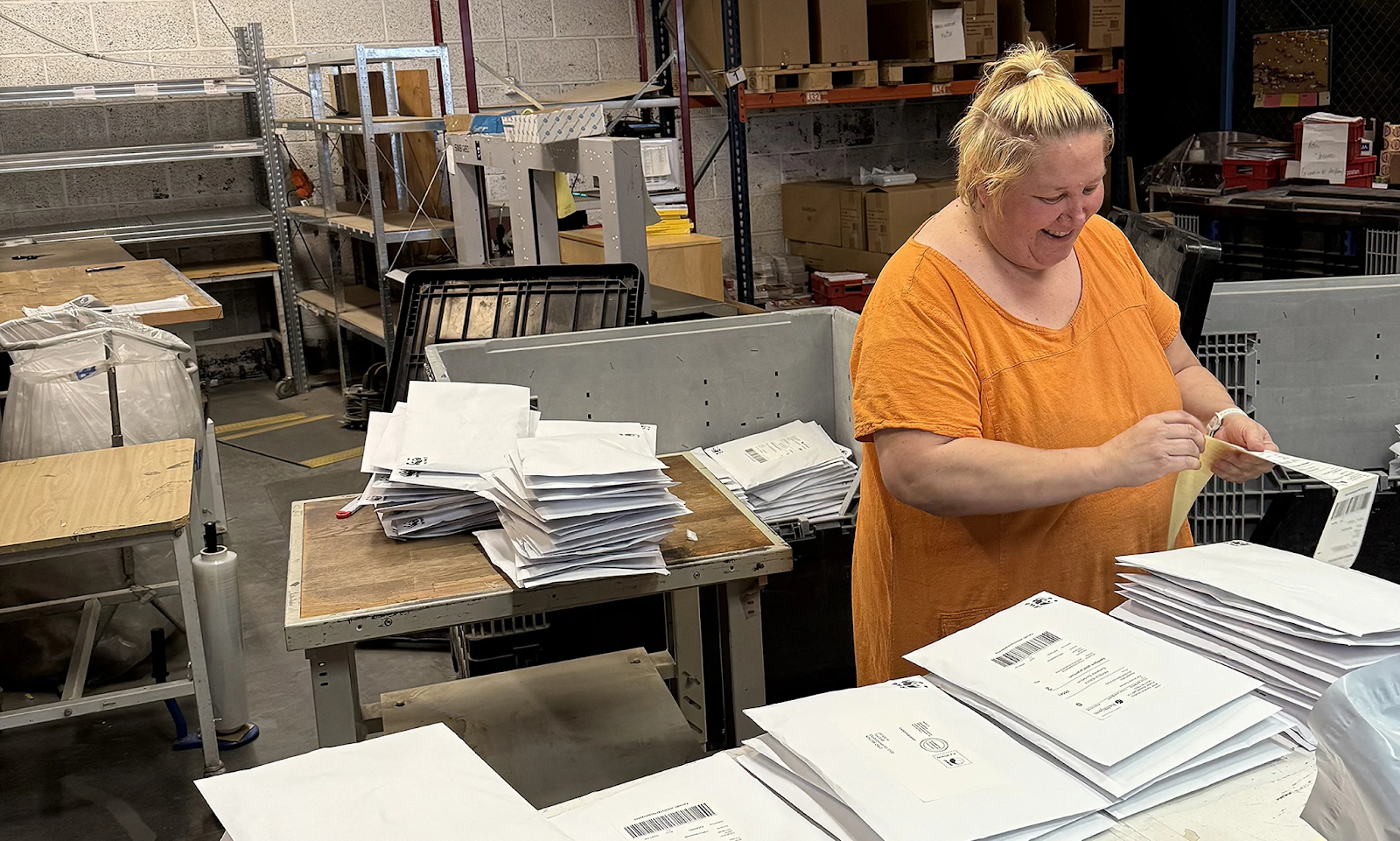 Manuell pakking utført av smilende kvinnelig kollega i Aksell logistikk